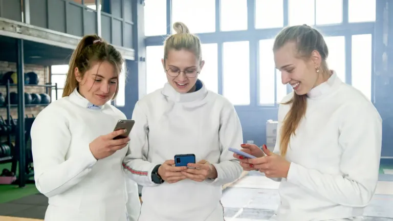 Sportives d'un club consultant les réseaux sociaux sur leur smartphone après l'entraînement