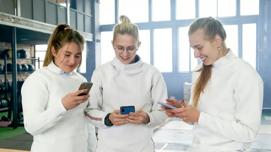 Sportives d'un club consultant les réseaux sociaux sur leur smartphone après l'entraînement