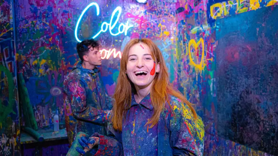 Joueuse riant dans la salle fluo de Color Room, couverte de peinture