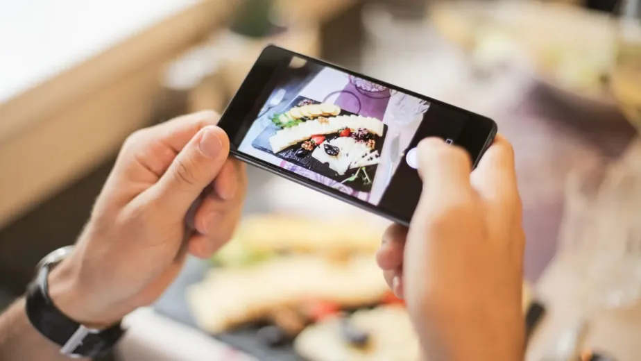 Restaurateur photographiant un plat avec son smartphone pour les réseaux sociaux du restaurant