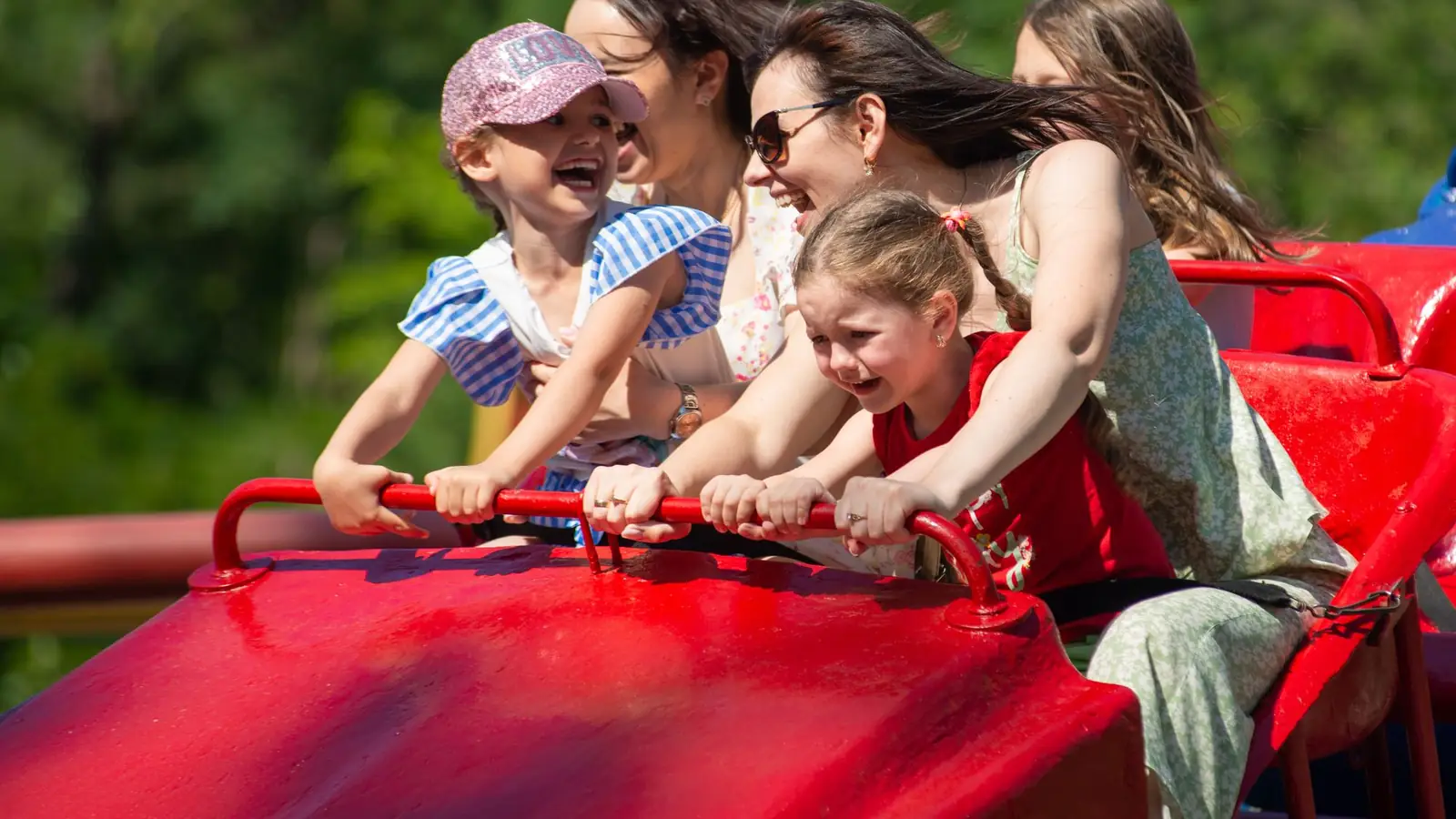 Mère et enfants riant sur un manège d'un parc de loisirs