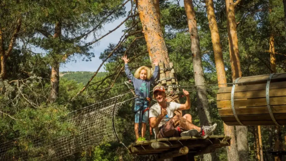 Enfants saluant depuis une plateforme d'un parc accrobranche