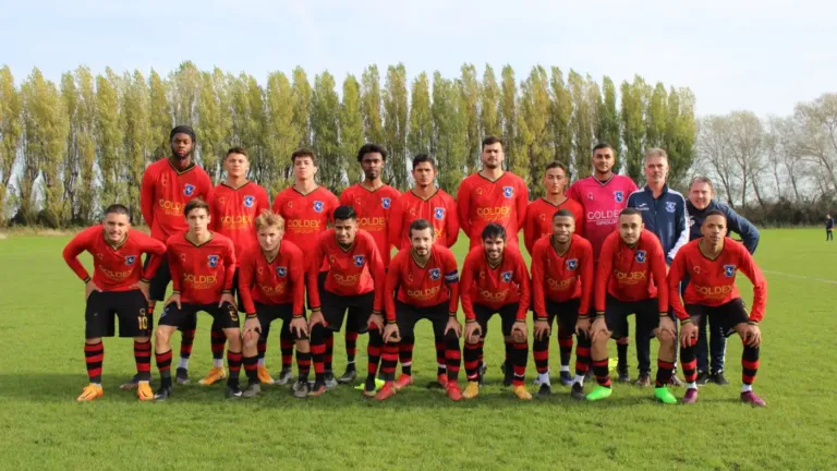 Équipe de football amateur posant sur le terrain en maillots de club